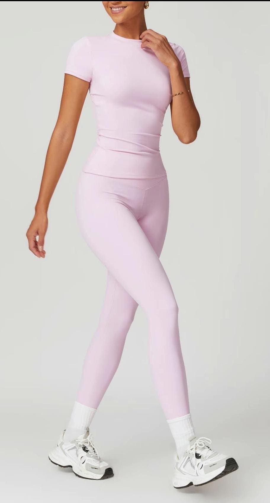 Woman in lavender yoga set and sneakers.